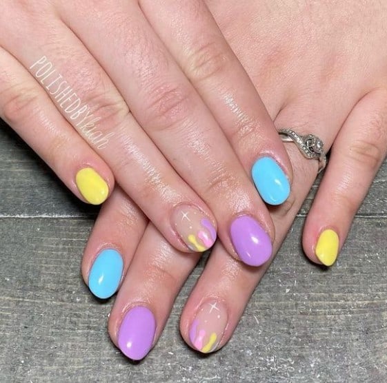 A woman's fingernails with multicolored pastel nail polish base that has dripping French tips on select nails