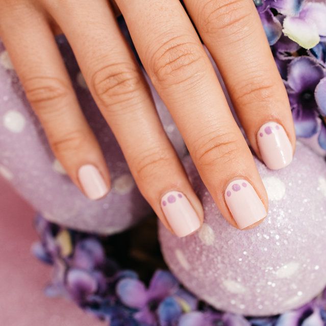 a woman's hand with light purple painted fingernails