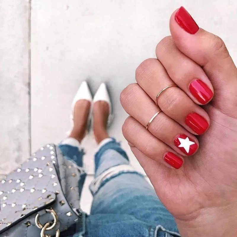 White star accent nail on bright red manicure