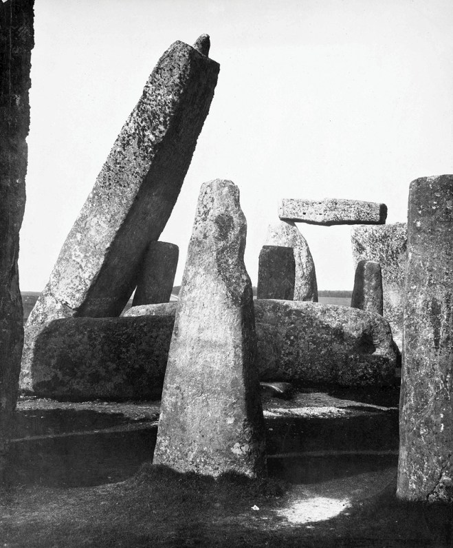 left The Great Trilithon and stone 56, pH๏τographed in 1881 by J J Cole. This leaning stone is a central element in the Romantic views of Stonehenge painted by Turner and Constable, and known through many reproductions; despite its alarming angle, there was no contemporary evidence that it was unstable. below The same group of stones, from the opposite direction, sH๏τ in the early 1890s with a group of German visitors leaning on stone 56. Improvements in road and rail transport made Stonehenge more accessible in the last decade of the 19th century.