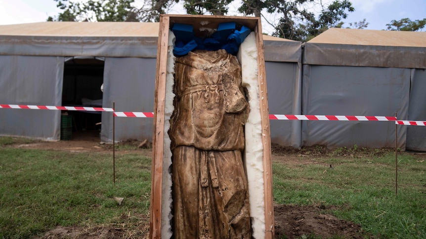 A headless status in a open casket held upright