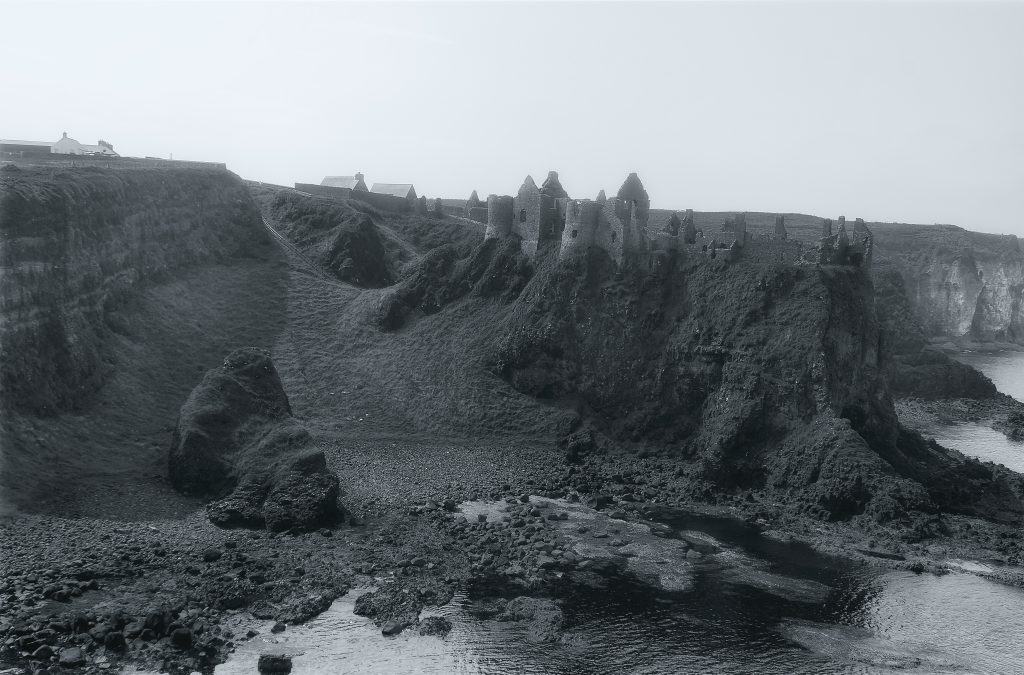 a black and white pH๏τo of a rocky coastline