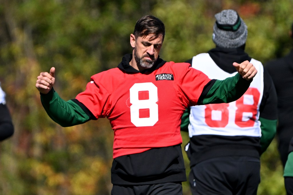 New York Jets quarterback Aaron Rodgers stretching during practice while dealing with a hamstring injury