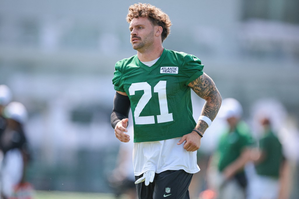 New York Jets safety Ashtyn Davis, wearing a green jersey and number 21, warms up during training camp at Atlantic Health Jets Training Center.