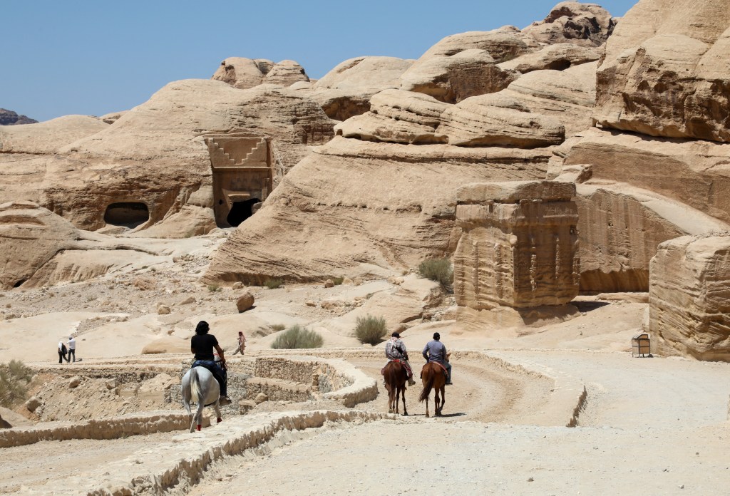 People riding horses while visiting the ancient city of Petra, south of Amman, Jordan, on August 25, 2024