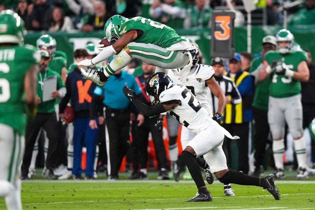 Eagles running back Saquon Barkley (26) hurdles over Jacksonville Jaguars cornerback Jarrian Jones (22) during the first half of an NFL football game Sunday, Nov. 3, 2024,