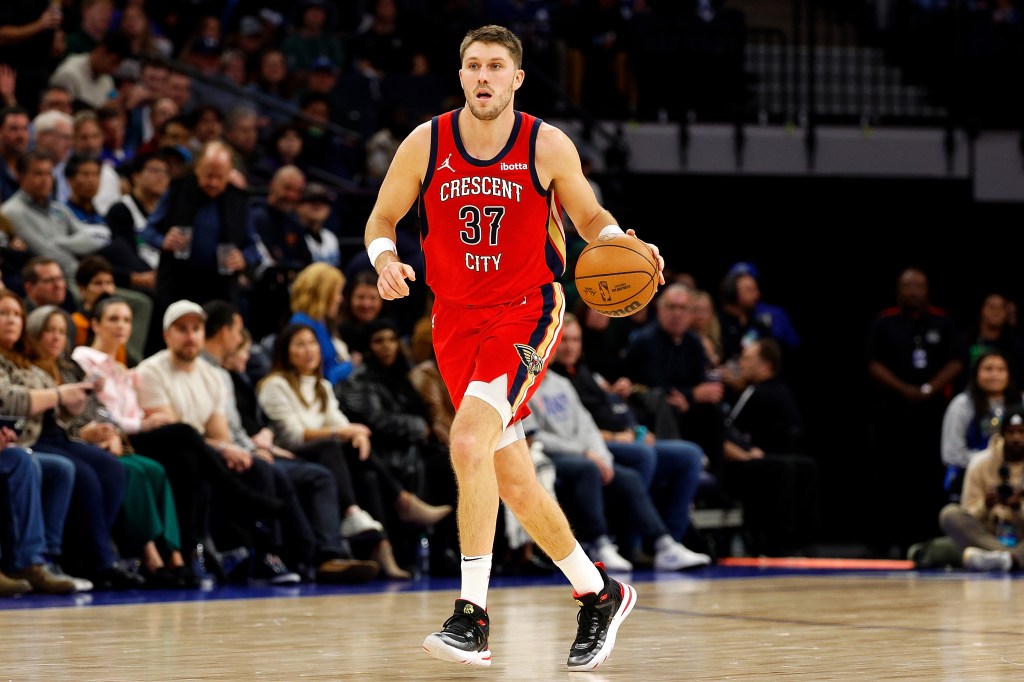 Matt Ryan of the New Orleans Pelicans, in red uniform, dribbling a basketball against the Minnesota Timberwolves in a basketball game.