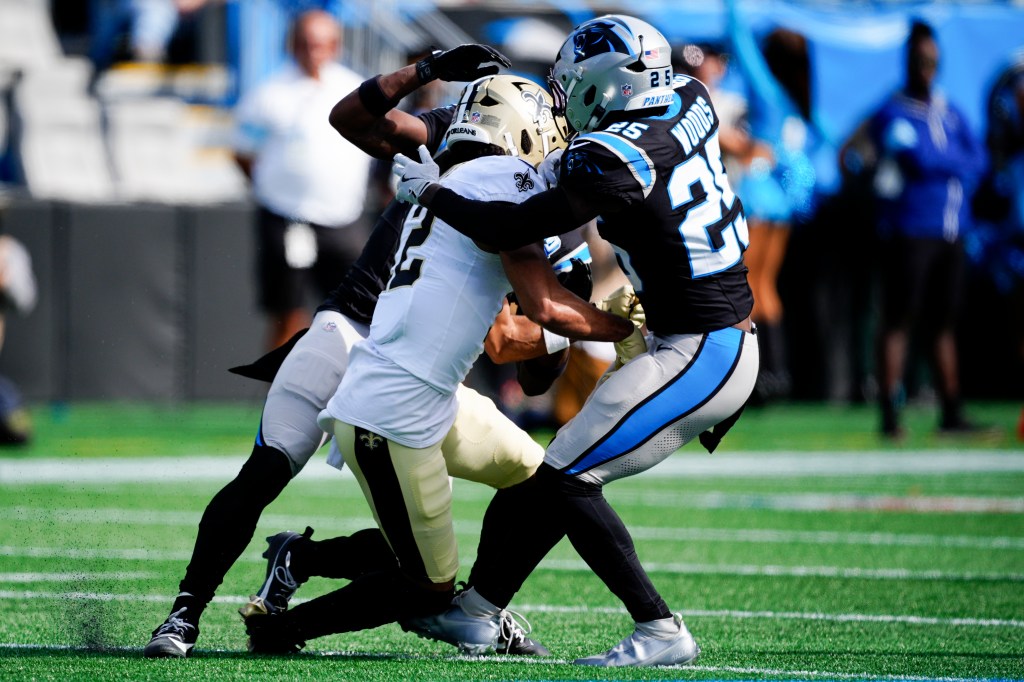 Saints receiver Chris Olave (12) is hit by Michael Jackson and Xavier Woods of the Panthers on Nov. 3, 2024.